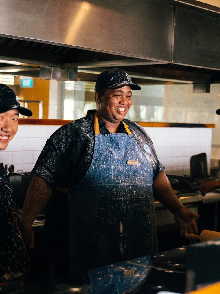 A smiling cook in an apron in a restaurant kitchen